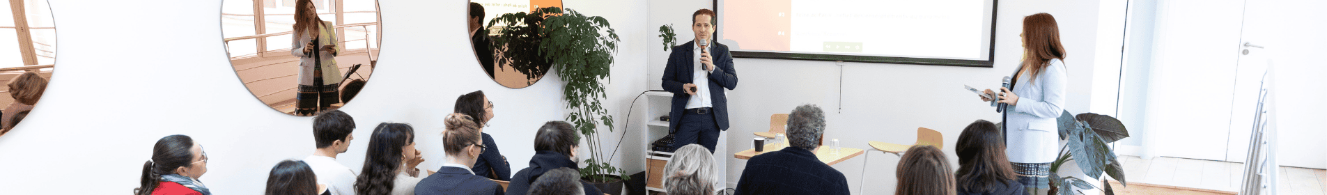 Un intervenant présente un sujet devant un public attentif lors d’une conférence professionnelle.