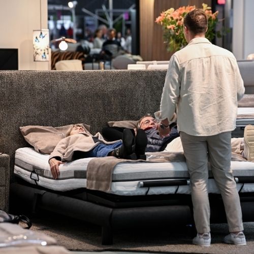 Des clients testent un lit en magasin pendant qu’un conseiller les accompagne dans leur choix.