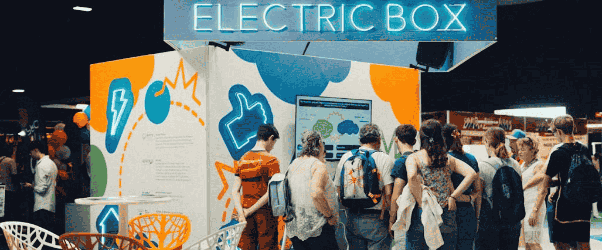 Stand Electric Box avec enseigne lumineuse et visiteurs rassemblés devant un écran lors d’un salon professionnel